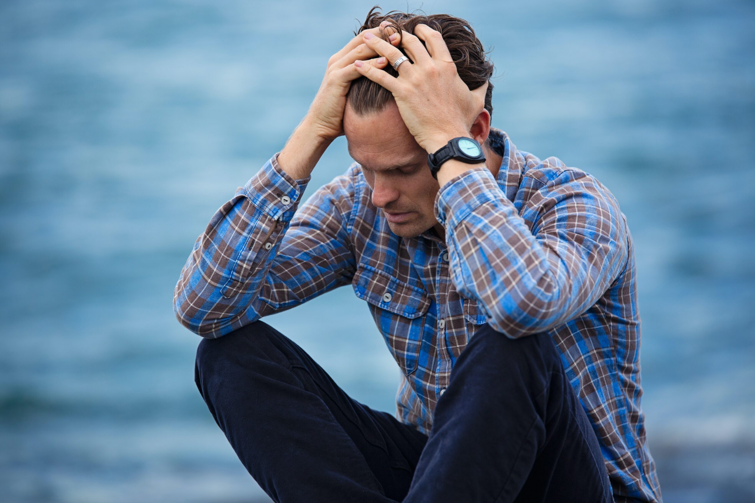 man suffering from alcoholism holding his head