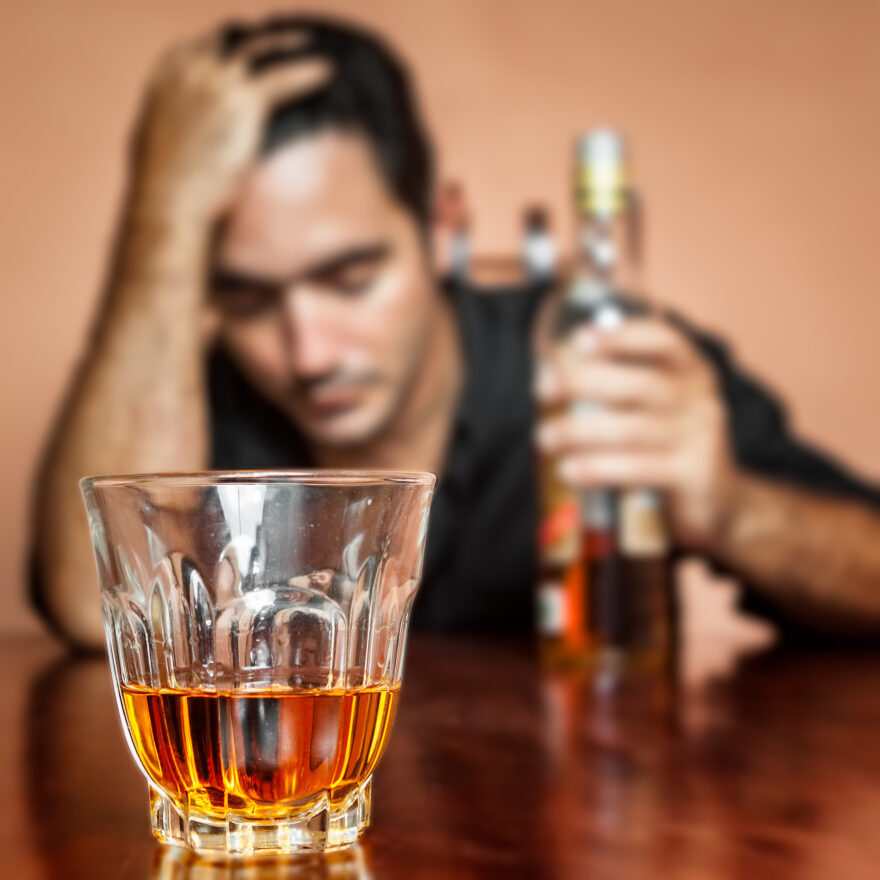 Drunk and lonely latin man holding a rum or whiskey bottle (image focused on his drink)